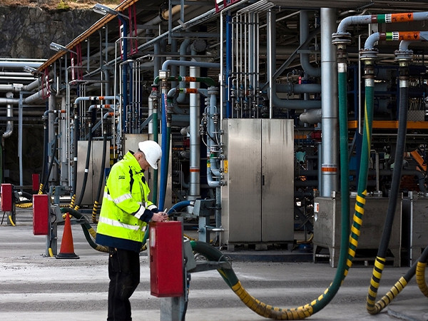 Workers inspecting pipelines in a factory filled with pipes.